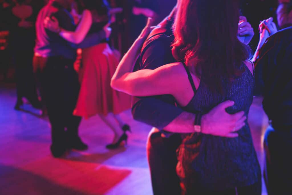 Couple enlacé dansant sous des lumières néon rouges et bleues. Ambiance festive et intime d'une soirée de danse.